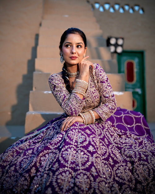 Woman in a purple and white traditional outfit sitting on steps outdoors.