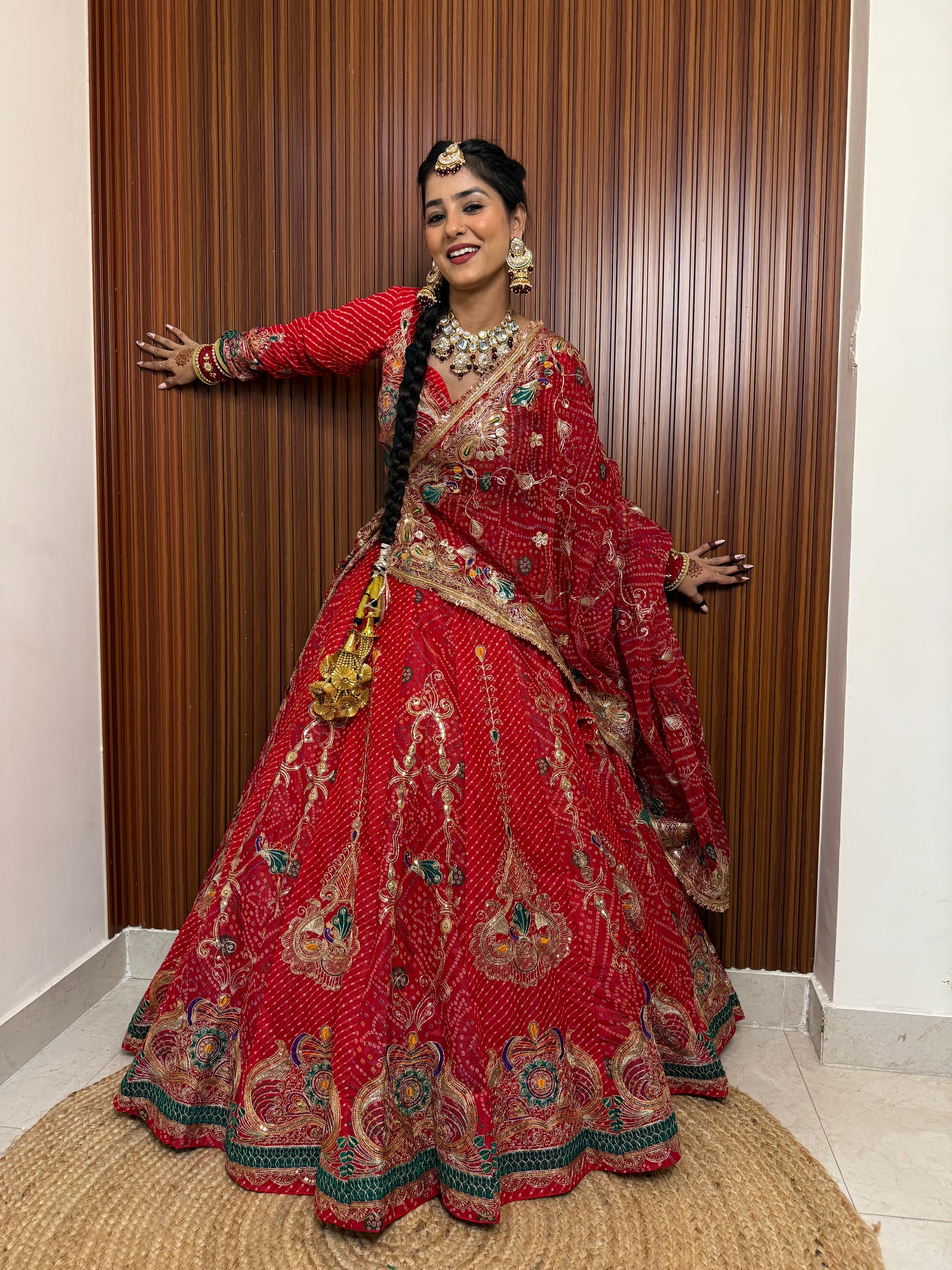 Woman in a traditional red and gold outfit posing indoors.