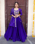 Woman in a purple traditional outfit standing in front of a decorated door.