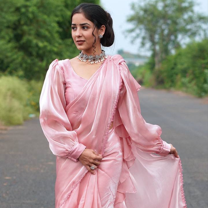 Woman in a pink saree standing on a road with greenery in the background