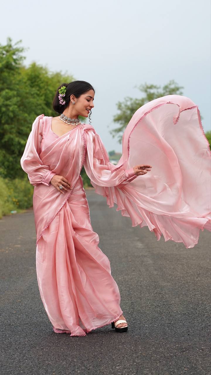 Woman in a pink saree standing on a road with trees in the background