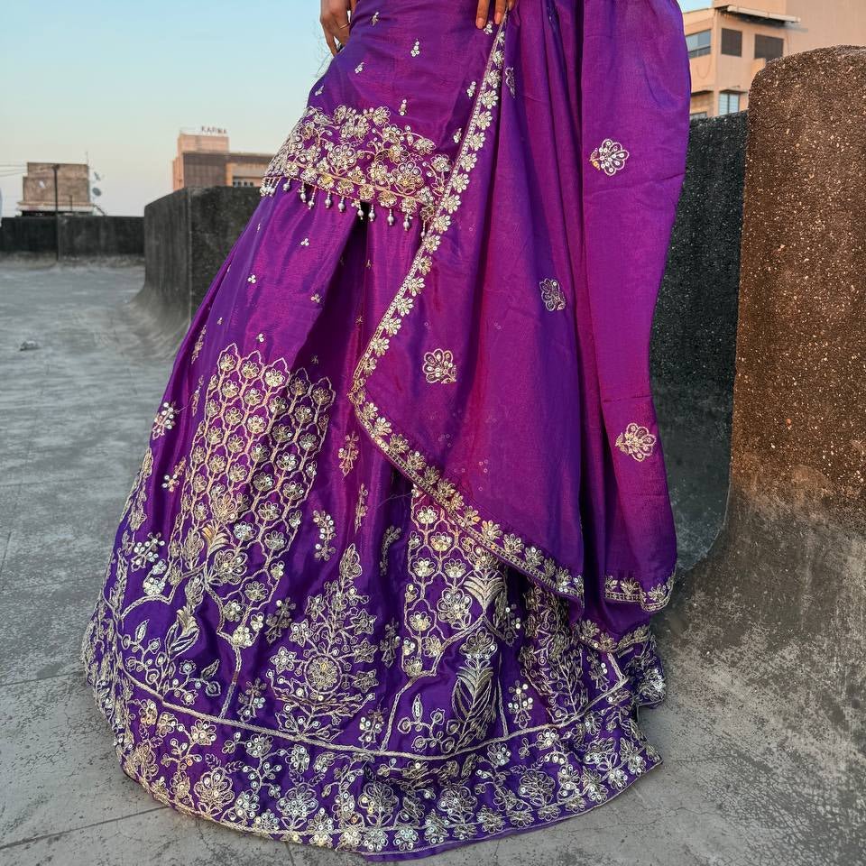Purple embroidered traditional outfit with a person holding it against an urban background.